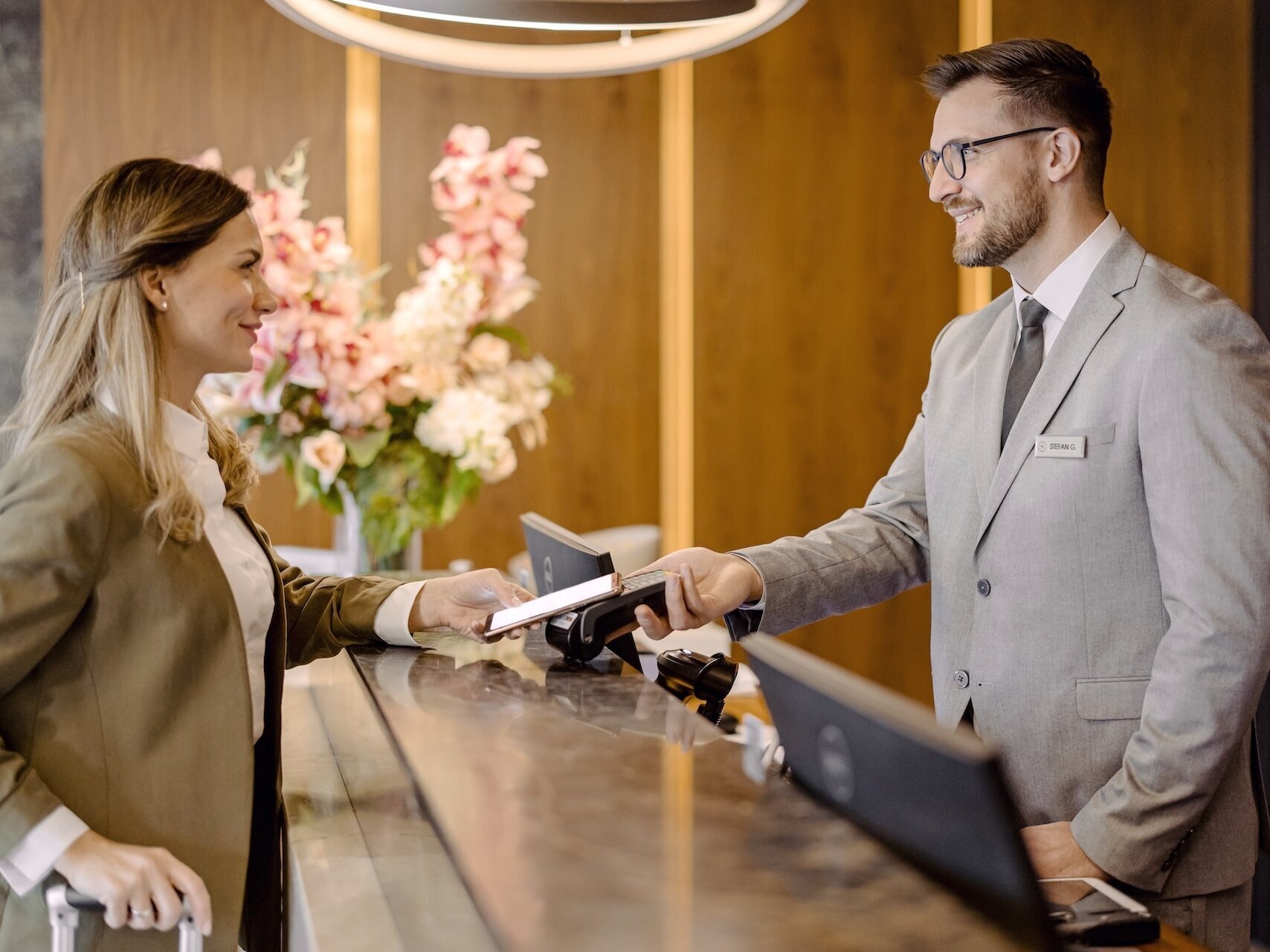 Frau checkt an Hotelempfang mit ihrem Smartphone ein. Beschreibt eine vernetzte Kommunikation für Kunden und Gäste. 